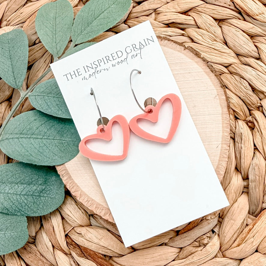 Heart-shaped earrings on a card with green leaves and woven surface