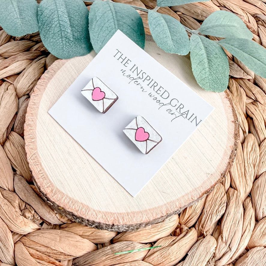 Earrings on a branded card with green leaves on a woven surface