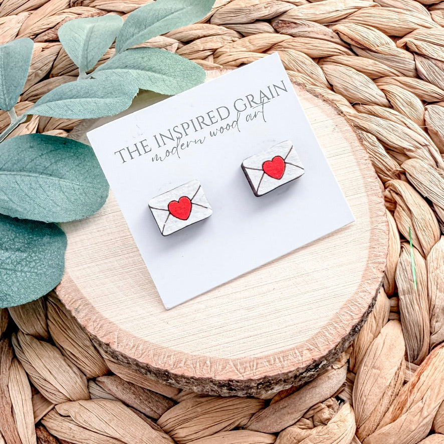 heart envelope earrings on a branded card with green leaves and woven surface