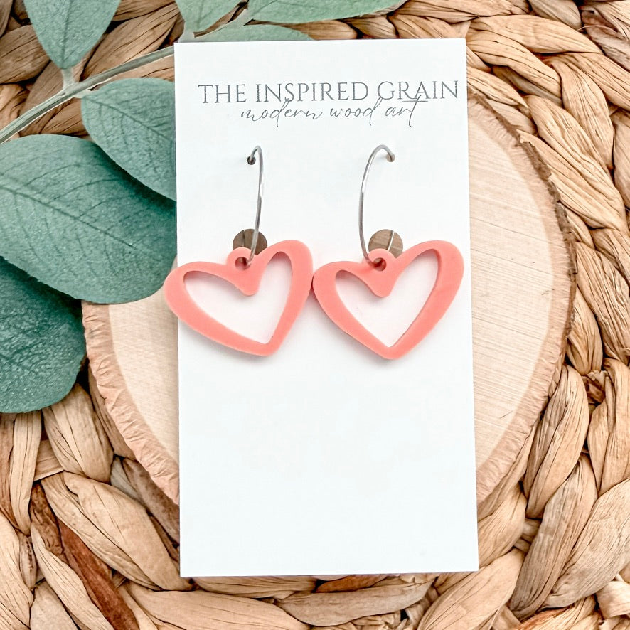 Heart-shaped earrings on a 'The Inspired Grain' branded card with leaves and wood in the background