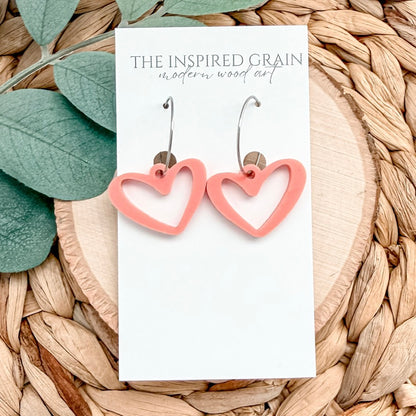 Heart-shaped earrings on a 'The Inspired Grain' branded card with leaves and wood in the background