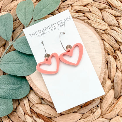 Heart-shaped earrings on a card with green leaves and woven surface