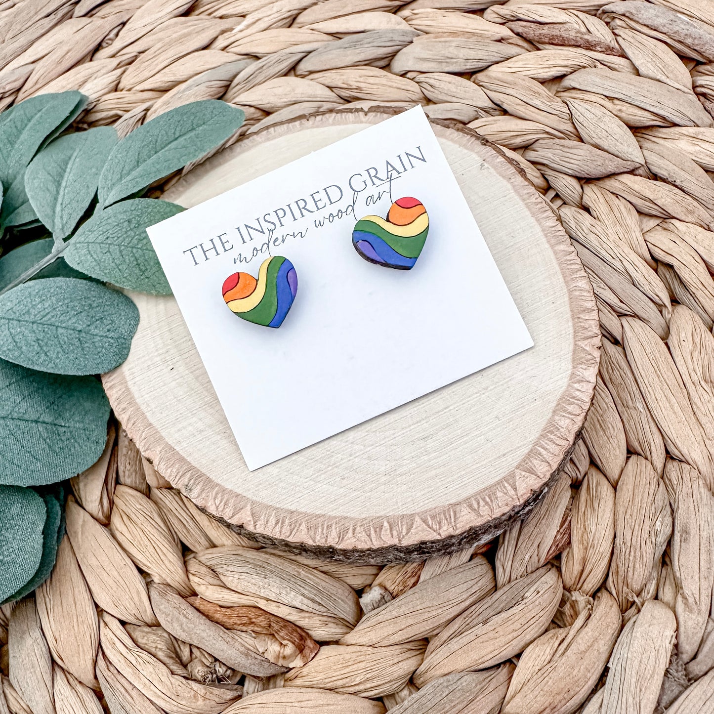 Rainbow heart earrings on a branded card with a natural background