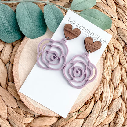 Purple rose-shaped earrings on a branded card with green leaves in the background