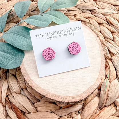 Pink rose-shaped earrings on a 'The Inspired Grain' branded card with leaves and wood background