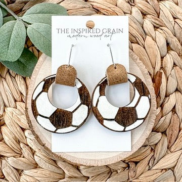 Soccer themed hoop earrings on a woven mat with 'The Inspired Grain' card.