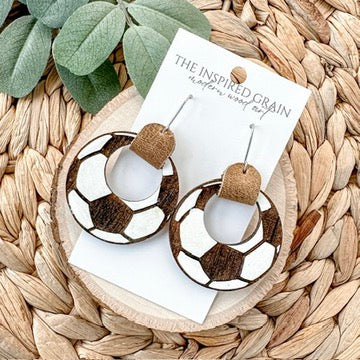 soccer themed hoop earrings on a woven surface with a card labeled 'The Inspired Grain'.