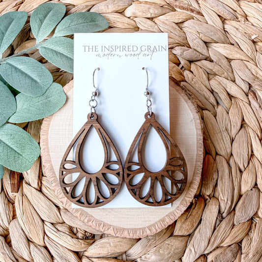 Wooden teardrop earrings on a 'The Inspired Grain' branded card with leaves and woven mat in the background.