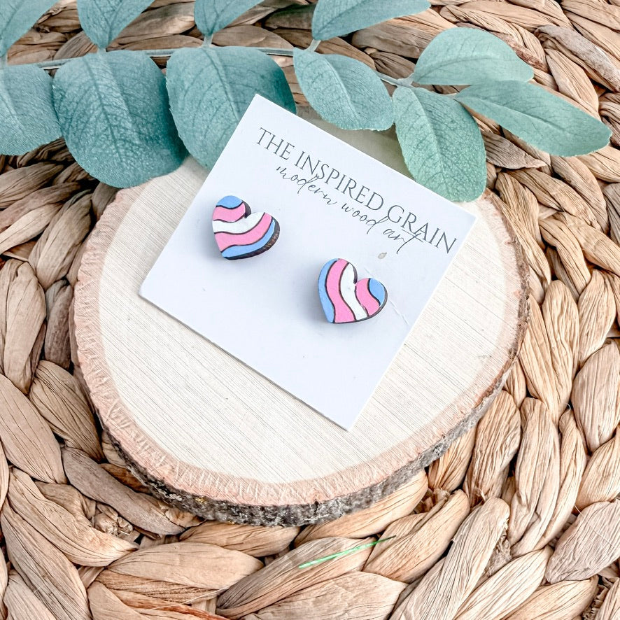 Colorful wavy-patterned heart shaped earrings on a branded card with green leaves in the background